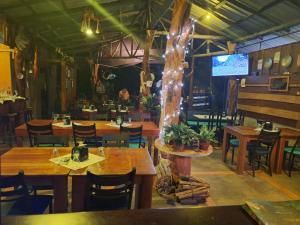 un ristorante con tavoli e sedie in legno e una televisione di Guapote Lodge a Tigra