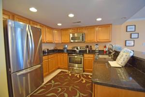 Bel Mare 101 condo في آوشين سيتي: مطبخ مع خزائن خشبية وثلاجة من الفولاذ المقاوم للصدأ