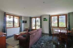 een woonkamer met een bank, een tafel en ramen bij Charming house with great views in Brison-Saint-Innocent