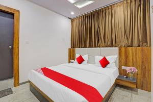 a bedroom with a large bed with red pillows at Collection O Hotel Dumas Rooms & Restaurant in Surat