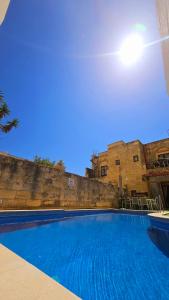 a large blue swimming pool in front of a building at Traditional Farmhouse Central Gozo in Xagħra