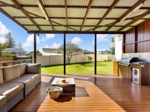 eine Terrasse mit einem Sofa und einem Tisch auf einer Terrasse in der Unterkunft Hibiscus Dreaming - Walking distance to the beach in Brooms Head