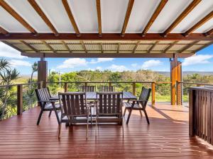 eine Terrasse mit Tisch und Stühlen auf einem Deck in der Unterkunft Hibiscus Dreaming - Walking distance to the beach in Brooms Head
