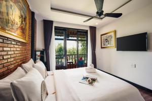 a bedroom with a large white bed with a tv at Art Museum Villa Hoi An in Hoi An