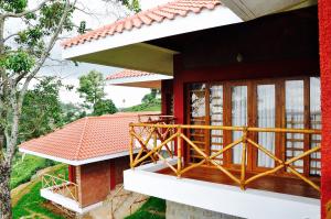 a house with a balcony with a red roof at Hanging Huts Resorts in Kotagiri