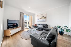 un salon avec un canapé en cuir noir et une télévision dans l'établissement In The Midst on Melbourne, à Adélaïde