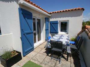 a table and chairs on a patio with blue doors at Maison La Tranche-sur-Mer, 2 pièces, 4 personnes - FR-1-22-327 in La Tranche-sur-Mer