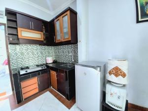 eine Küche mit braunen Schränken und einem weißen Kühlschrank in der Unterkunft Homestay Jogja Simply Homy Unit Ambarukmo 3 dekat Jogja Expo Center JEC in Bantul
