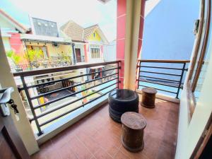 ein Balkon mit zwei Hockern und Blick auf ein Haus in der Unterkunft Homestay Jogja Simply Homy Unit Ambarukmo 3 dekat Jogja Expo Center JEC in Bantul