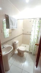 a white bathroom with a toilet and a sink at HOSTAL ACUARIUS PUNO in Puno