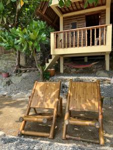 duas cadeiras de madeira sentadas em frente a uma casa em L'Astrolabe - Beach Kubo em Baras