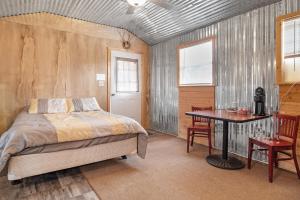 a bedroom with a bed and a desk and a table at Great Heart Whitefield Cabin 1 in Bandera