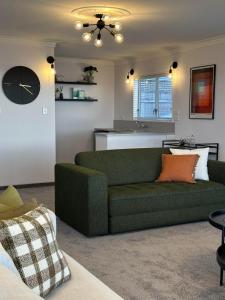 a living room with a green couch and a kitchen at Hamblyn Heights Stunning Seaviews in New Plymouth in New Plymouth