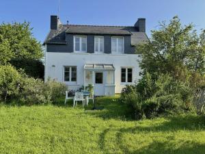 a white house with a table in the yard at Maison typique proche plage de Kerleven et golf, calme, jardin reposant, services de conciergerie - FR-1-481-165 in La Forêt-Fouesnant