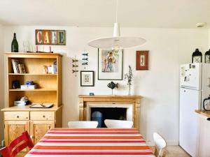 a dining room with a table and a refrigerator at Maison typique proche plage de Kerleven et golf, calme, jardin reposant, services de conciergerie - FR-1-481-165 in La Forêt-Fouesnant