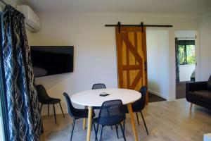 a living room with a table and chairs and a television at The Guest House in Tamahere