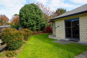 a house with a grass yard next to a building at The Guest House in Tamahere