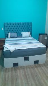 a large bed in a room with a blue wall at 5x Hostal in Puerto Callao