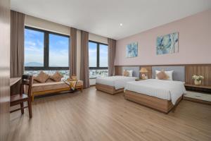 een slaapkamer met 2 bedden, een bank en ramen bij ATP Galaxy Hotel & Apartment Danang in Da Nang