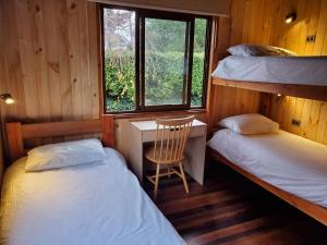 two beds in a room with a desk and a chair at Lucky's Hostel in Pucón