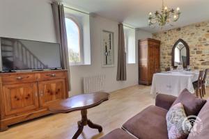 a living room with a couch and a tv and a table at L'etang in Mézières-sur-Couesnon