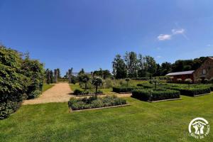 a garden with bushes and trees and a pathway at L'etang in Mézières-sur-Couesnon