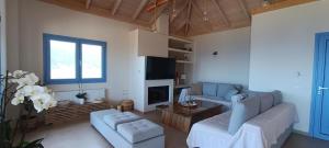 a living room with a couch and a tv at Augustela Villa SeaView Vacation Villa in Ayia Evfimia