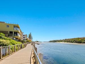 a boardwalk next to a beach and a building at Bare Feet Retreat in Kingscliff