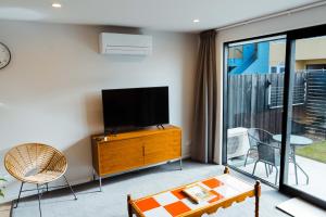 a living room with a flat screen tv and a table at New townhouse, 300m 4 minute walk Te Kaha One New Zealand Stadium, car park, 2 bed 2 bath in Christchurch