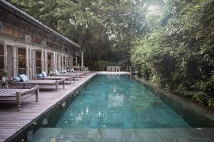 une piscine avec bancs et arbres en arrière-plan dans l'établissement Balquisse Heritage Hotel, à Jimbaran
