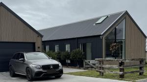 レイク・テカポにあるThe Landsborough Tekapoの黒い建物の前に停車する車