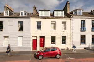 Un coche rojo aparcado delante de un edificio blanco. en Greyfriar's Snug, en St Andrews