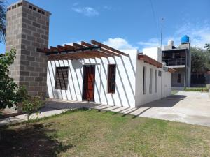 a small white building with a red door at terraza con asador privado in Termas de Río Hondo