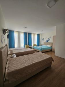 two beds in a hotel room with blue curtains at Apartments LOTUS in Gevgelija