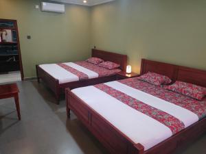 una camera con due letti con lenzuola rosse e bianche di Mango Guesthouse a Pangandaran