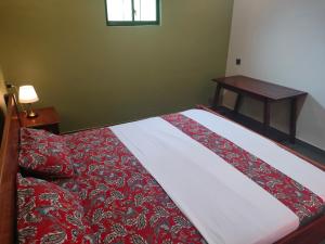 una camera con un letto e un piumone rosso e bianco di Mango Guesthouse a Pangandaran Altre 22 foto