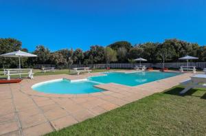 a swimming pool with a picnic table and benches at Cute condo with garden and BBQ in Plettenberg Bay