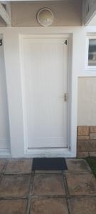a white garage door on a white house at Cute condo with garden and BBQ in Plettenberg Bay