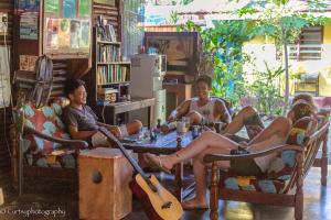 a group of people sitting around a table with a guitar at Gecko Guesthouse in Pantai Cenang