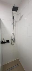 a shower in a bathroom with white tile walls at Pension Wolfi in Gersdorf