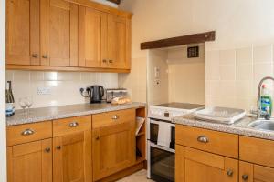 eine Küche mit Holzschränken und einer Spüle in der Unterkunft Watermouth Castle, South Court Apartment in Ilfracombe + 25 Fotos