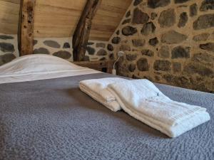 a white blanket laying on a bed with a stone wall at Buron de Léon, en plein cœur de l Aubrac in Laguiole