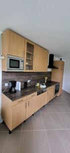 a kitchen with wooden cabinets and a microwave at Pension Wolfi in Gersdorf