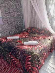una camera con un letto con un piumone rosso e nero di Tapuhere Lodge a Fare (Huahine Nui)