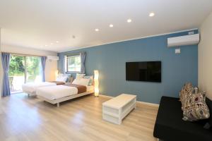 une chambre avec deux lits et une télévision à écran plat dans l'établissement スターダストヴィラミルキーウェイ, à Fukai