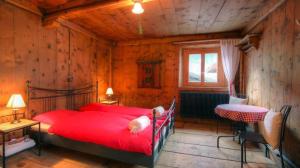 a bedroom with a large red bed and a table at Chasa Jaro in Santa Maria Val Müstair +29 photos