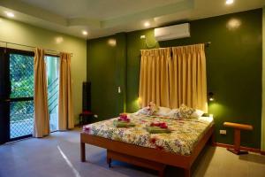 a green bedroom with a bed with flowers on it at Vista Verde, Family Living in Puerto Princesa City +14 photos