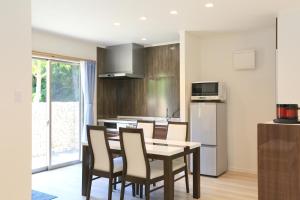 une cuisine avec une table et des chaises dans une pièce dans l'établissement スターダストヴィラミルキーウェイ, à Fukai