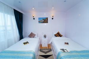 two beds in a room with white walls at Turquoise in Luxor