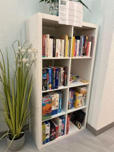 une étagère remplie de livres à côté d'une plante dans l'établissement Center, Sauna - Haus LINARIA, à Loèche-les-Bains